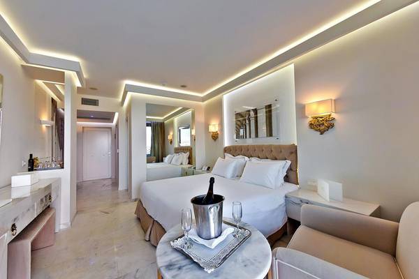 Innenansicht einer Suite im Royal Marmin Bay Boutique Hotel mit großem Bett, Tisch und Champagner