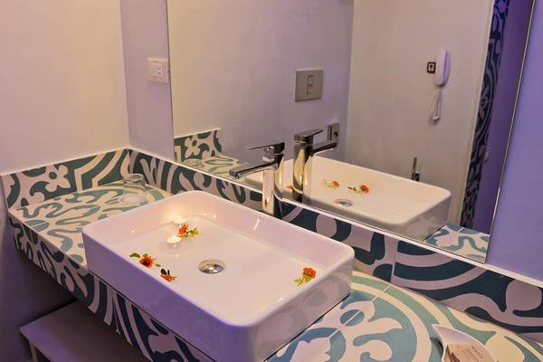 Badezimmer des Royal Marmin Bay Boutique Hotels mit luxuriösem Waschbecken und blau-weißem Wanddesign.