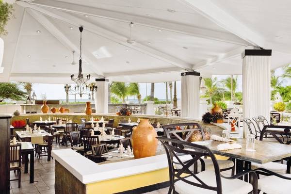 Innenbereich des Amsterdam Manor Beach Resort Restaurants mit Tischen, Stühlen und einem Blick auf die Meereslandschaft.