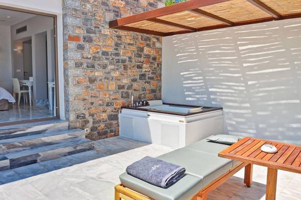 Außenbereich des Royal Marmin Bay Boutique Hotels mit Whirlpool und Liegestuhl.