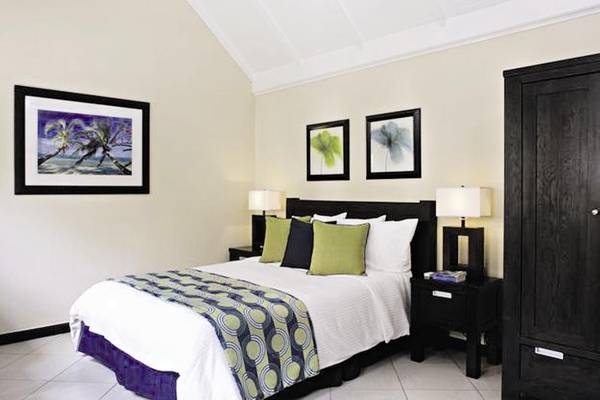 Hotelzimmer im Amsterdam Manor Beach Resort mit Bett, Kissen, Lampen und Gemälden.