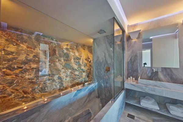 Luxuriöses Badezimmer im Royal Marmin Bay Boutique Hotel mit Marmorwänden und Badewanne.