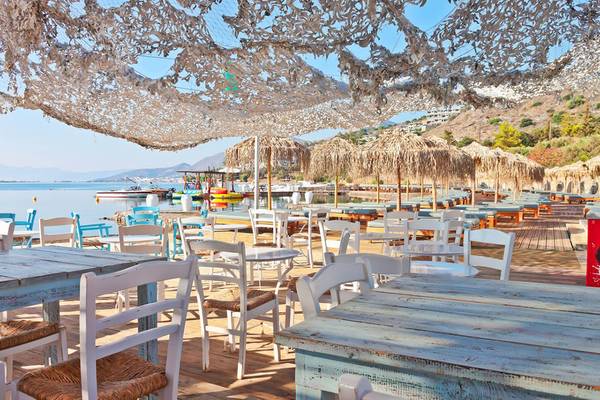 Terrasse des Royal Marmin Bay Boutique Hotels mit Tischen, Stühlen und Sonnenschirmen.