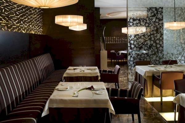 Das elegante Restaurant des Gran Melia Palacio de Isora mit gedeckten Tischen, Stühlen und Kronleuchtern.