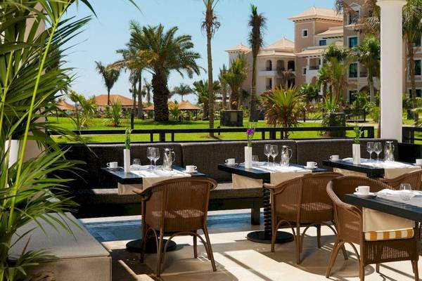 Außenterrasse des Gran Melia Palacio de Isora Hotel mit Blick auf eine gepflegte Landschaft und Gebäude.