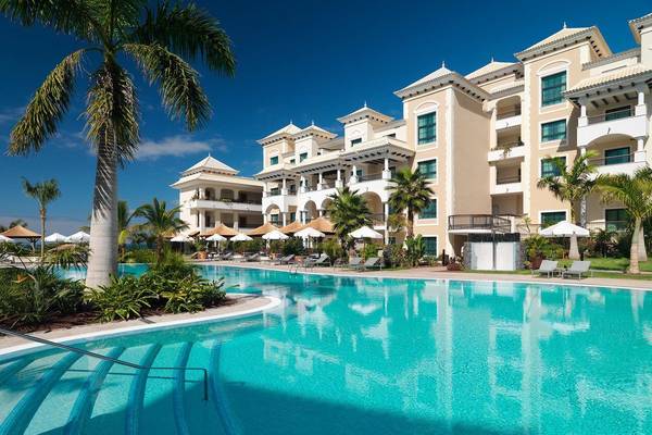 Außenpool des Gran Melia Palacio de Isora Hotels mit Loungeliegen und Palmen