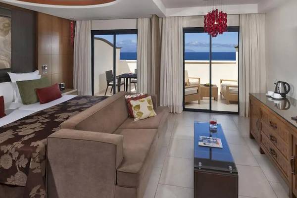 Gran Melia Palacio de Isora Suite Zimmer mit Meerblick, großes Bett, Couch, Tisch, Fernseher und Balkon.