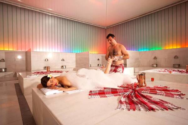 Spa-Behandlung im Adam & Eve Hotel mit einem Mann, der eine Frau mit Schaum bedeckt.