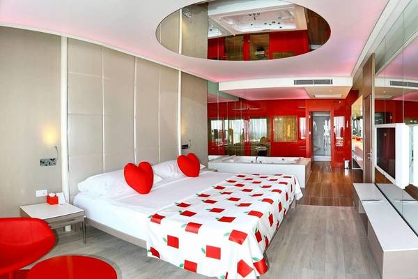Adam & Eve Hotel Schlafzimmer mit rotem Herzen, Badewanne, Fernseher und Spiegelwänden.