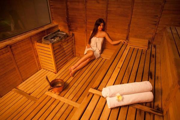 Eine Frau in einem weißen Handtuch sitzt auf einer Bank in der Sauna des Hotels Adam & Eve.