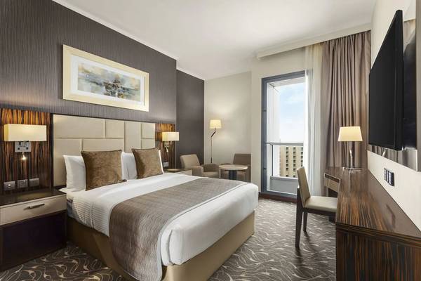 Hotelzimmer von Hawthorn Suites Abu Dhabi mit Bett, Schreibtisch, Sesseln und Fenster.