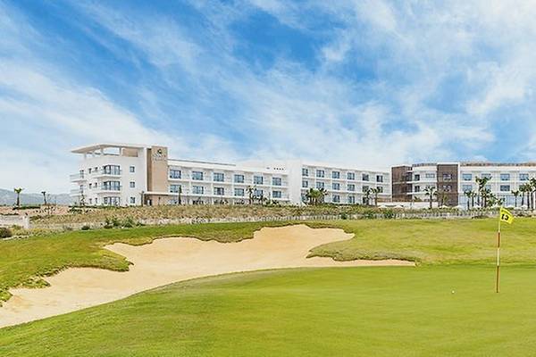 Golfplatz vor dem Hyatt Place Taghazout Bay Hotel mit einem Golfwagen und einem gelben Flaggenstecker.