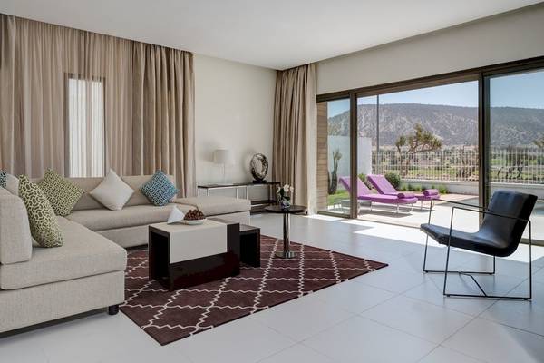 Innenansicht des Wohnbereichs im Hyatt Place Taghazout Bay Hotel mit moderner Einrichtung und Aussicht auf die Berge.