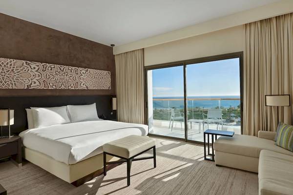 Hotelzimmer mit großem Bett, Couch, Meerblick und Glasterrasse im Hyatt Place Taghazout Bay.