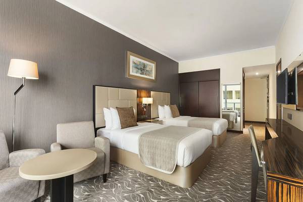 Hotelzimmer von Hawthorn Suites Abu Dhabi mit zwei Betten, Lampe, Tisch und Spiegel.
