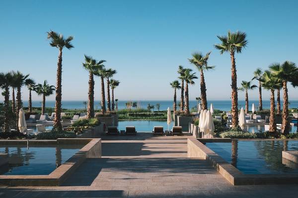Außenpoolbereich des Hyatt Place Taghazout Bay mit Palmen und Blick auf das Meer