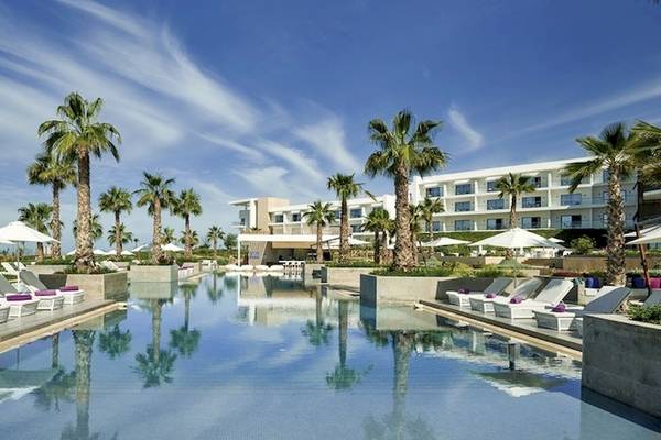 Außenpool des Hyatt Place Taghazout Bay Hotels mit Lounge-Liegestühlen und weißen Sonnenschirmen.