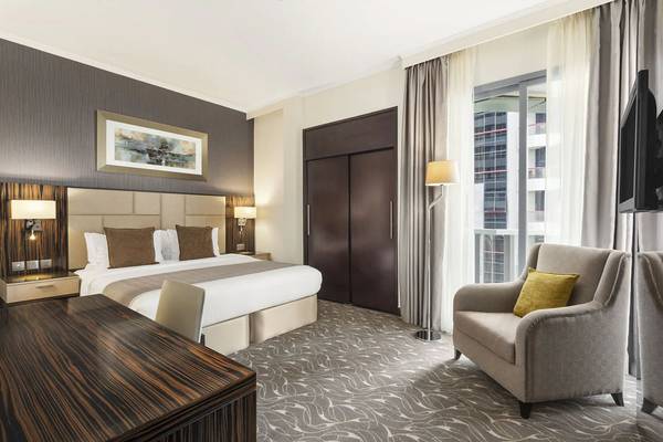 Hotelzimmer im Hawthorn Suites Abu Dhabi mit Bett, Schreibtisch, Sessel und Fernseher.
