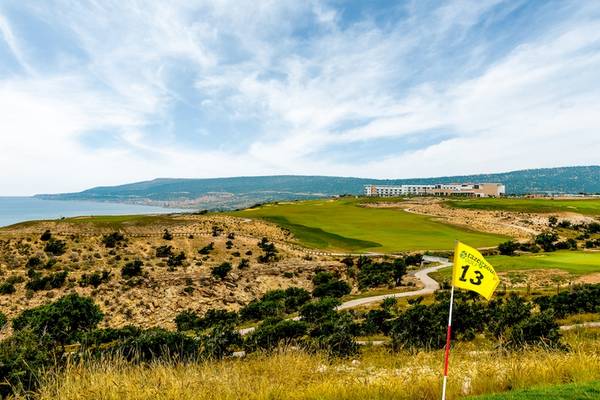 Golfplatz mit Blick auf das Meer und das Hyatt Place Taghazout Bay Hotel in der Ferne.
