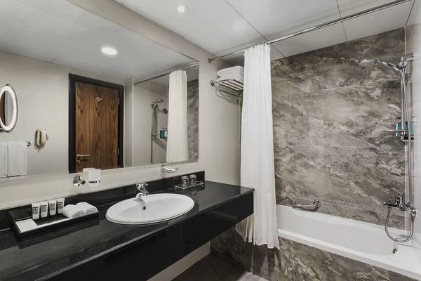 Badezimmer im Hawthorn Suites Abu Dhabi Hotel mit Waschbecken, Badewanne und Dusche.