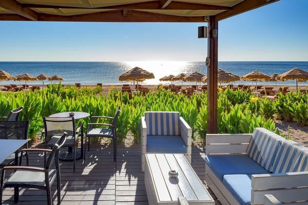 Aussicht auf den Strand des La Marquise Luxury Resort Complex mit Sonnenuntergang und Sonnenschirmen