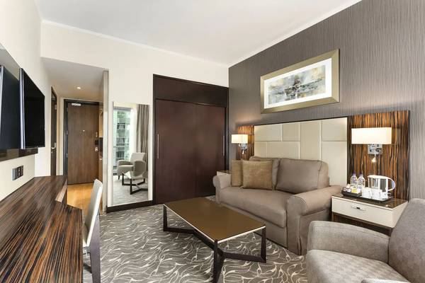 Innenansicht eines Hotelzimmers im Hawthorn Suites Abu Dhabi mit Sofa, Schreibtisch und Fernseher.