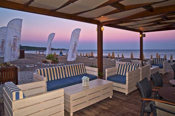 Terrasse des La Marquise Luxury Resort Complex bei Sonnenuntergang mit Blick auf den Strand und das Meer.