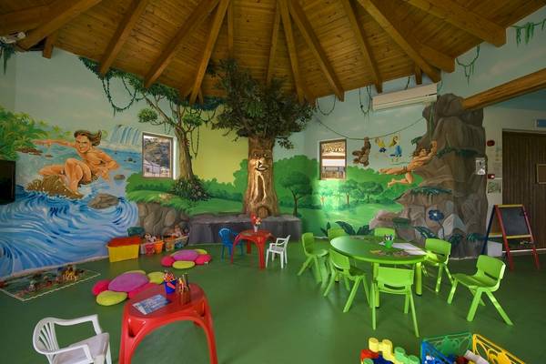 Kinderzimmer im La Marquise Luxury Resort Komplex mit grünen Möbeln und farbigen Wandmalereien.