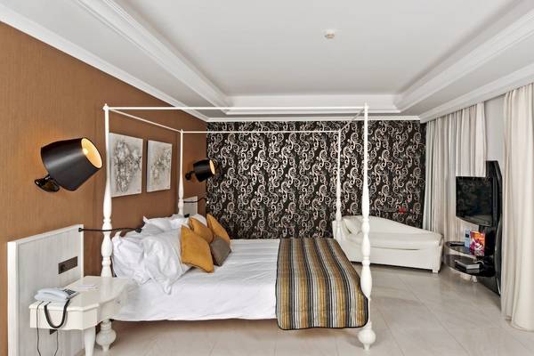 Schlafzimmer im La Marquise Luxury Resort Complex mit vierpfostenbett, Wandtapeten und Fernseher.