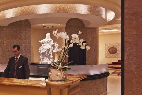 Rezeption des La Marquise Luxury Resort Complex mit einem Mann und einer Frau, Statue und Blumen im Hintergrund.