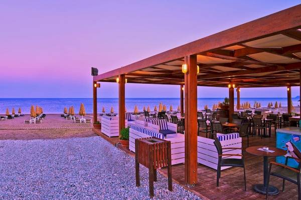 Strandbar des La Marquise Luxury Resort Complex mit Blick auf den Ozean und Sonnenschirmen.