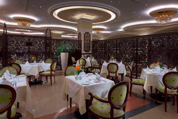 Restaurant-Innenansicht des La Marquise Luxury Resort Complex mit gedeckten Tischen und kunstvollen Wandschirmen.