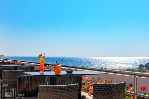 Terrasse des La Marquise Luxury Resort Complex mit Blick auf das Meer und Cocktails auf den Tischen.