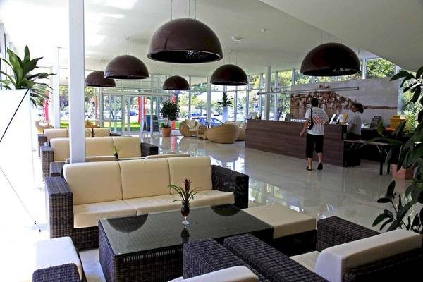 Lobby des Amadria Park Beach Hotel Jure mit Sitzmöbeln, Tischen und großen Lampen