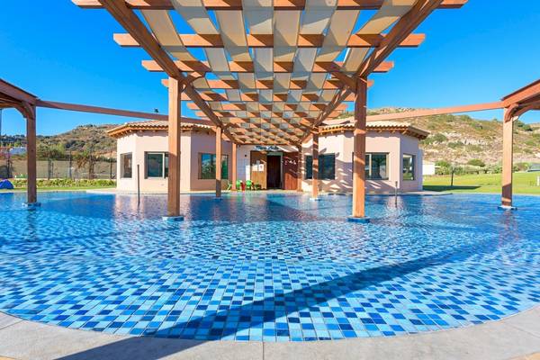 Schwimmbad des La Marquise Luxury Resort Complex mit Pergola und Gebäuden im Hintergrund.