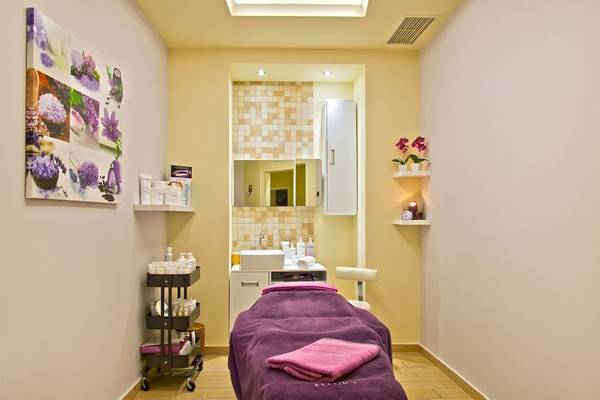 Behandlungsraum im Spa des La Marquise Luxury Resort Complex mit hellen Wänden, Möbeln und einer Liege mit violettem Handtuch.