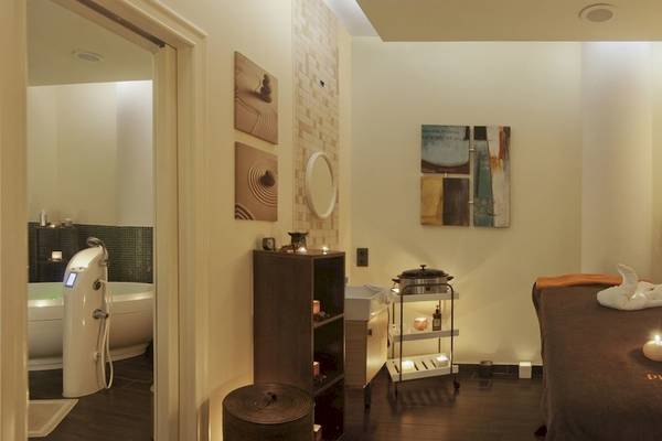 Spa-Behandlungsraum im La Marquise Luxury Resort Complex mit Badewanne, Kerzen und Massagetisch.