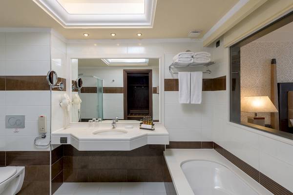Badezimmer im La Marquise Luxury Resort Complex mit Badewanne, Spiegel und Handtüchern.
