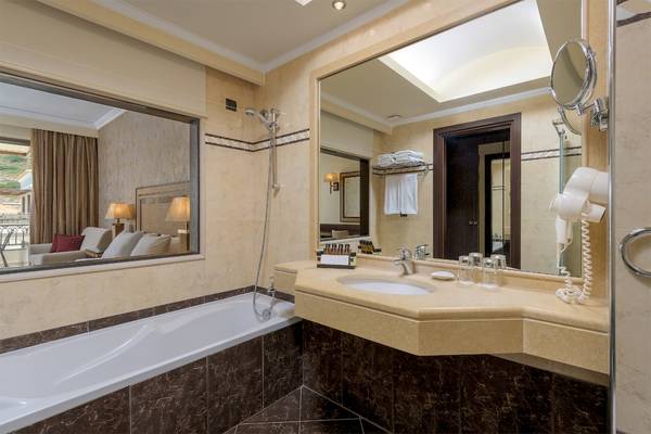 Badezimmer im La Marquise Luxury Resort Complex mit Badewanne, Spiegel und Föhn.