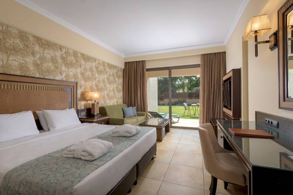 Hotelzimmer im La Marquise Luxury Resort Complex mit Doppelbett, Schreibtisch, Sessel und Gartenaussicht.