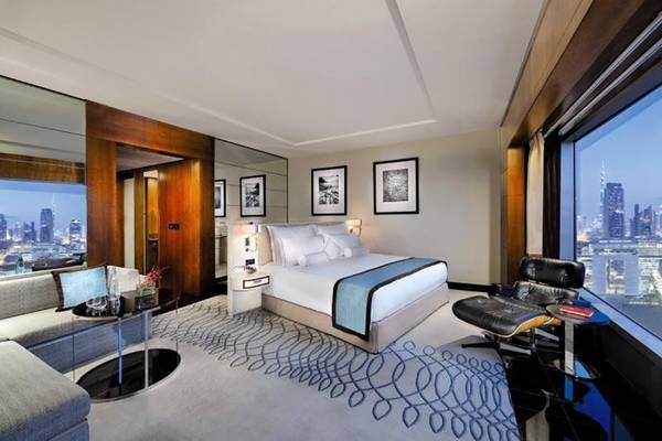 Ein Hotelzimmer im Jumeirah Emirates Towers mit einem Bett, einem Wohnzimmerbereich und einer Aussicht auf die Stadt.