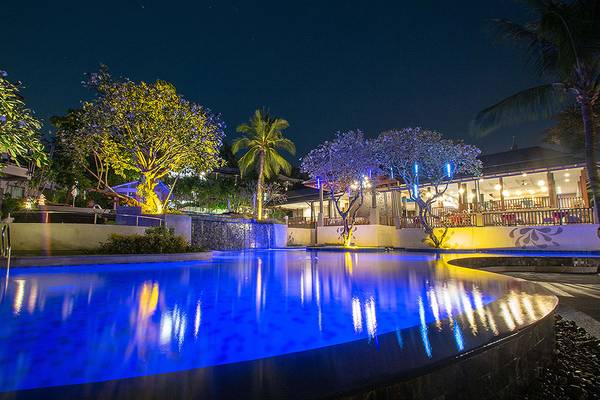 Der Außenpool des Andaman Cannacia Resorts bei Nacht mit blauen Lichtern und Pflanzen.