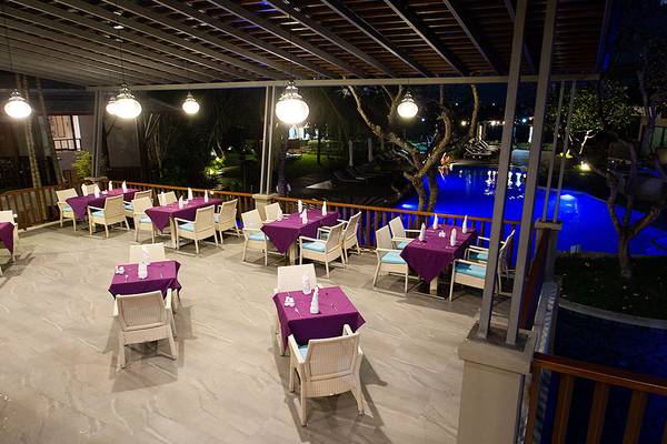 Außenbereich des Andaman Cannacia Resorts mit Tisch und Stuhl, bei Nacht mit Poolbeleuchtung.