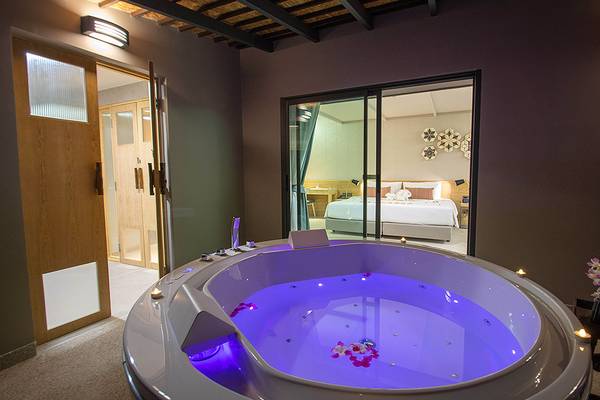 Suite im Andaman Cannacia Resort mit Jacuzzi, Blick auf ein Bett und Schlafzimmer.