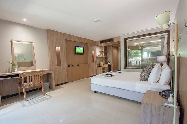 Innenansicht eines Hotelzimmers im Andaman Cannacia Resort mit Bett, Schreibtisch und Fernseher.