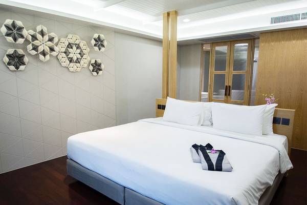 Ein elegantes Zimmer im Andaman Cannacia Resort mit einem weißen Bett und dekorativen Elementen.