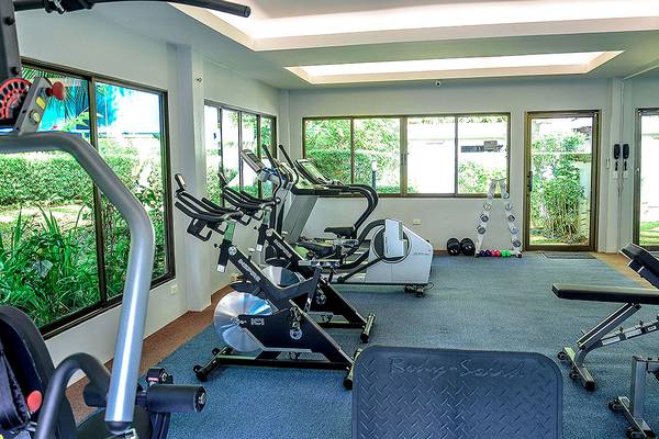 Fitnessraum im Andaman Cannacia Resort mit Cardiogeräten und Fenstern.