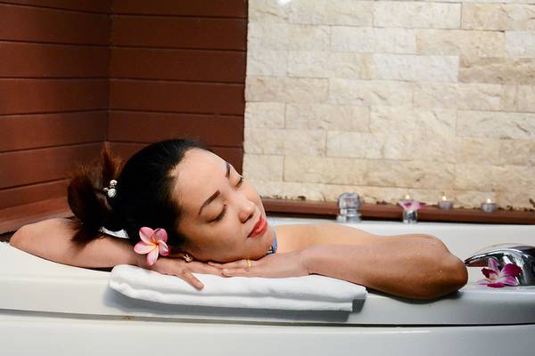 Frau im Badewanne mit Blumen im Andaman Cannacia Resort