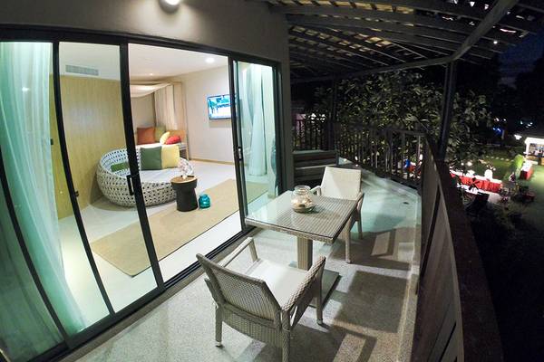 Nachtansicht des Balkons des Andaman Cannacia Resorts mit Glastüren, Möbeln und Garten.