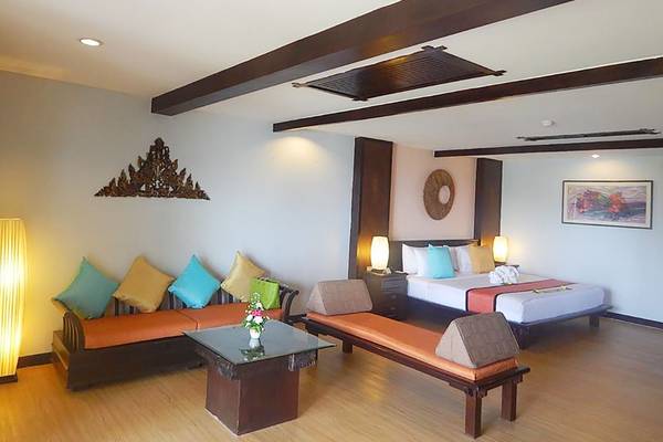 Ein modernes Hotelzimmer im Andaman Cannacia Resort mit einem Bett, einem Sofa, einem Tisch und einem Stehlicht.